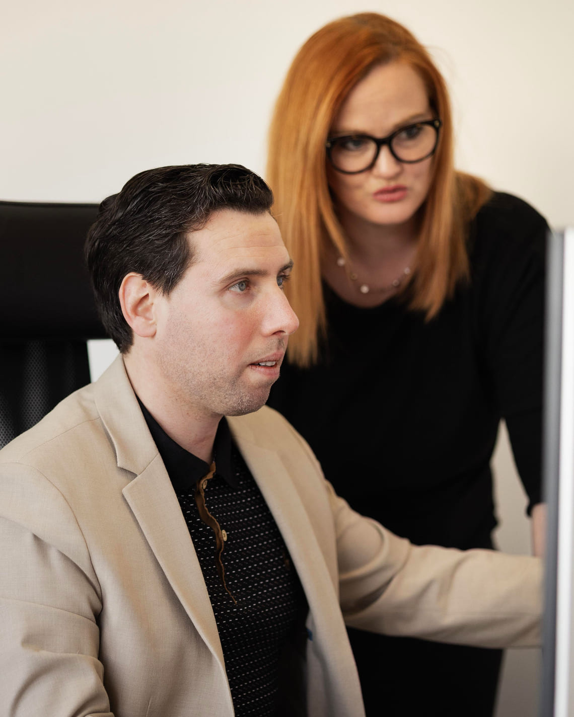 Grégory Di Palma et une collaboratrice examinent ensemble un écran de travail, concentrés sur les données affichées