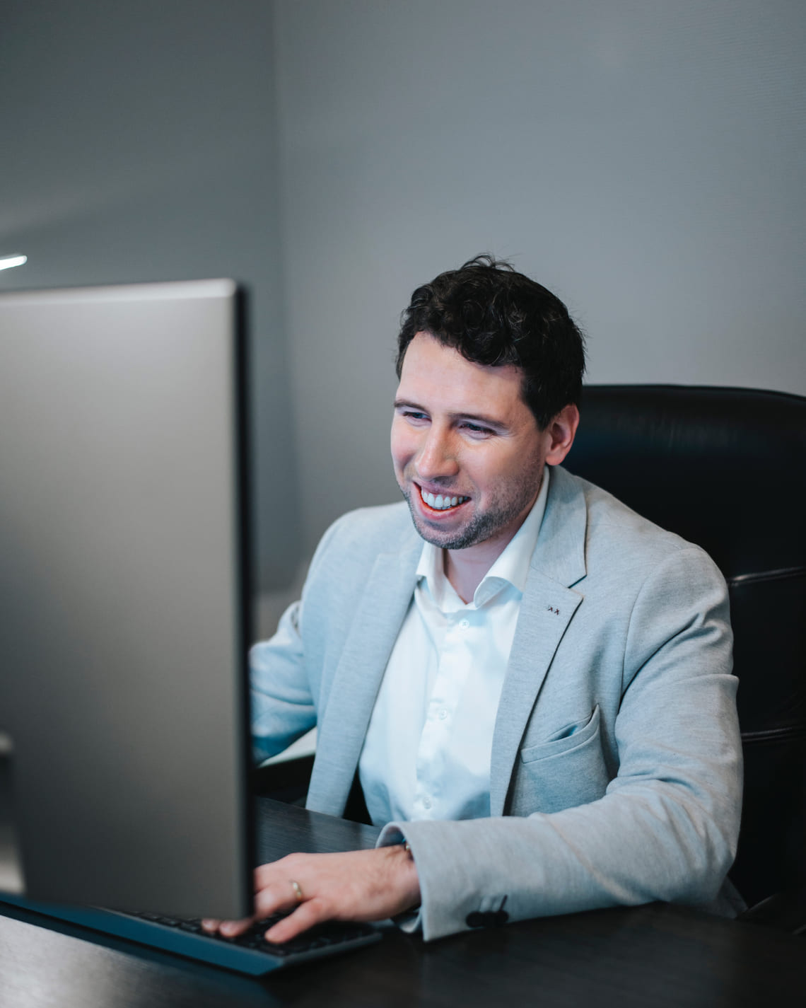 Grégory Di Palma, souriant devant son écran, teste un outil d’intelligence artificielle à son bureau